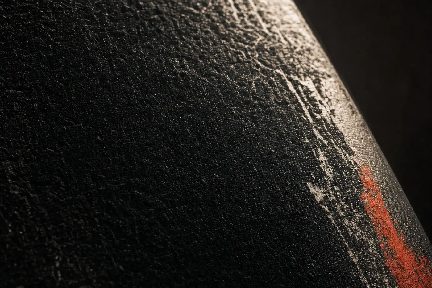 La surface d'un tatami noir, éclairée de biais, avec une bande rouge sur le bord.